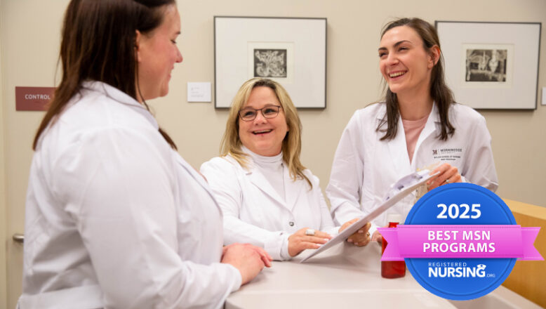 two female nurse practitioners stand with the female dean of the program at a counter all in white coats.